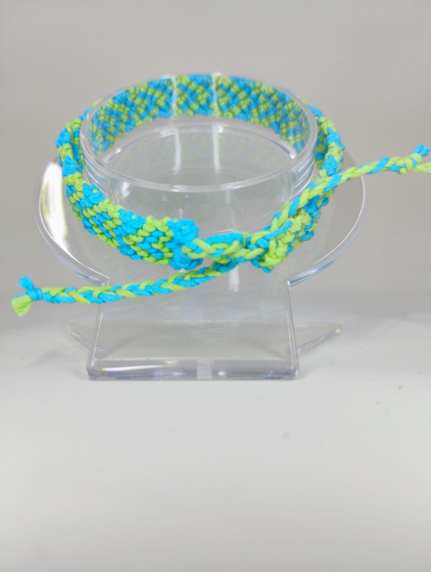 Hand knitted bracelet in green with blue colors, woven heart design.